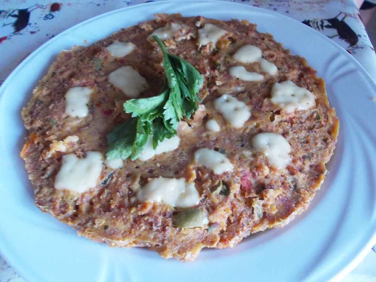 Frittata rustica con accumoli di formaggio e rametto di prezzemolo fresco, servita su piatto bianco