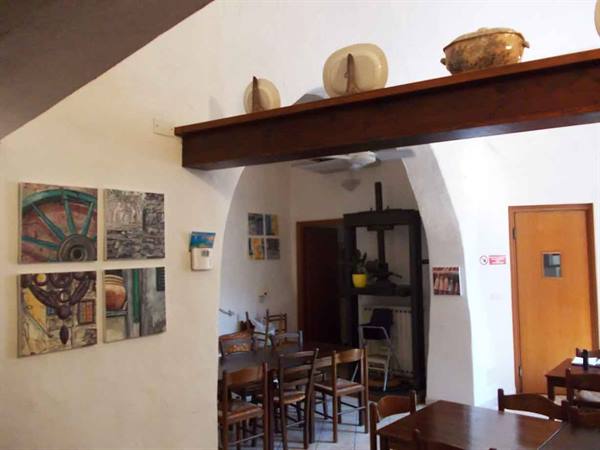 Trattoria with wooden beams, ceramics, paintings and old wine press under white arches
