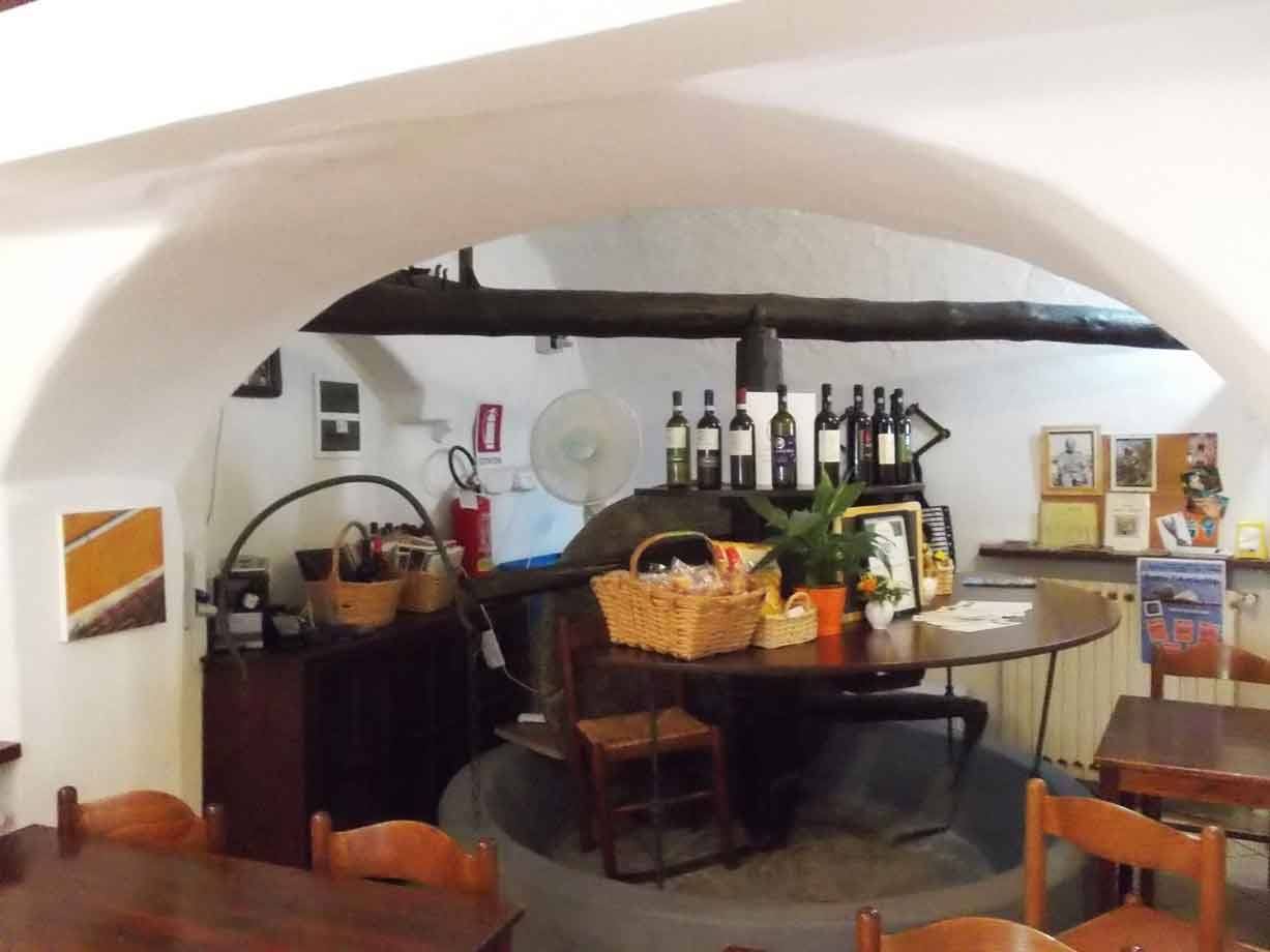 Interno con antico mulino in pietra, bottiglie di vino e ceste sul tavolo