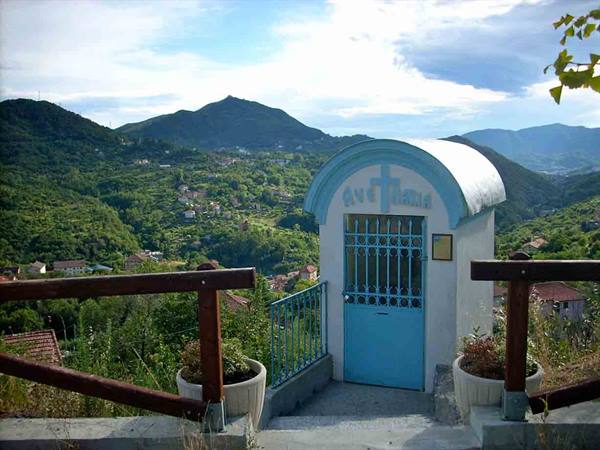 Small blue votive shrine with cross among green hills