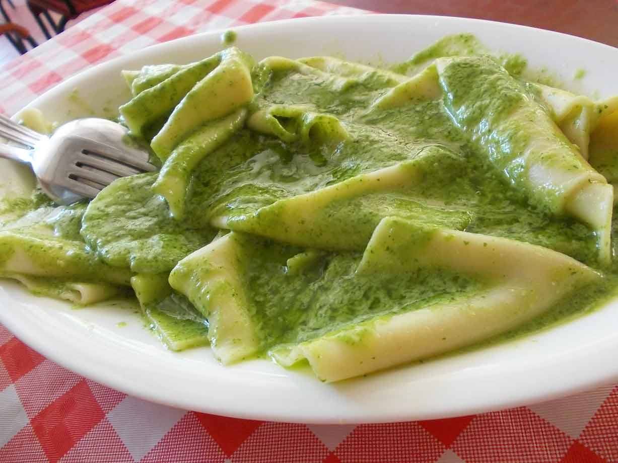 Paccheri con salsa verde sul piatto bianco, tovaglia a quadri rossa