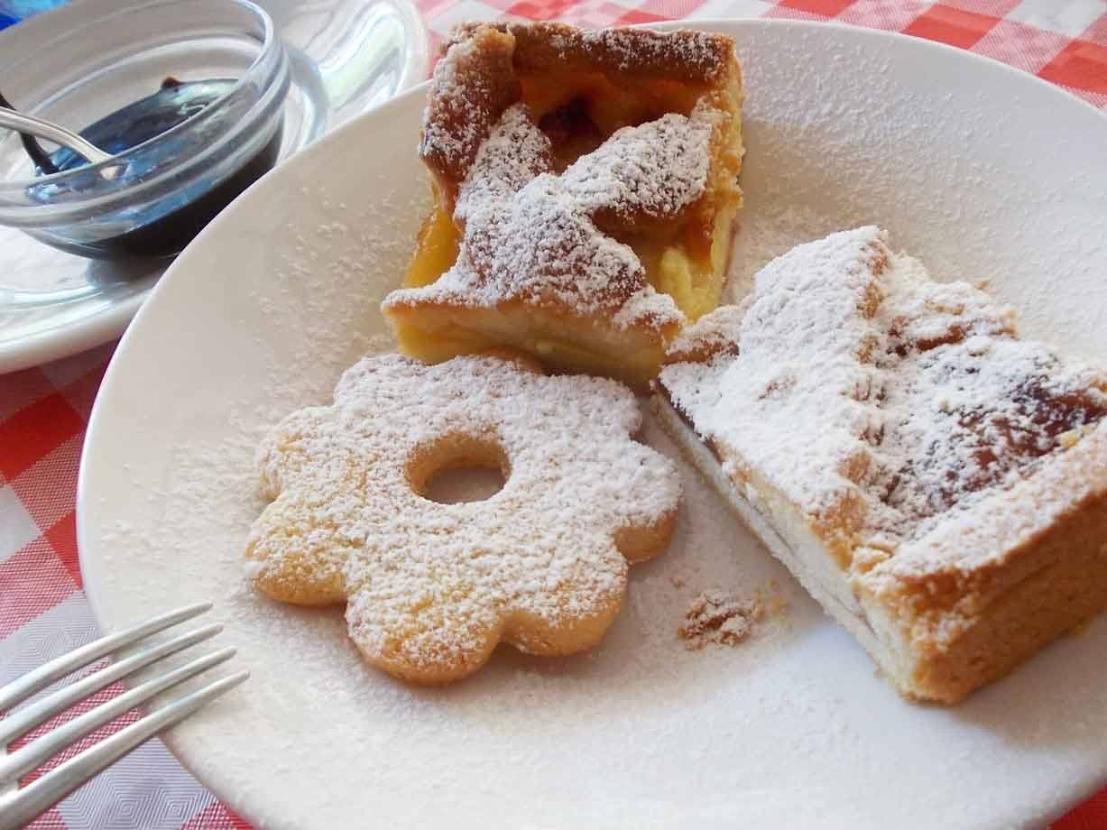 Dolci spolverati di zucchero a velo su piatto bianco, tovaglia rossa a quadri