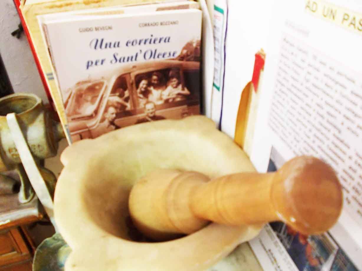 Mortaio di marmo con pestello di legno davanti a libri e vecchie fotografie
