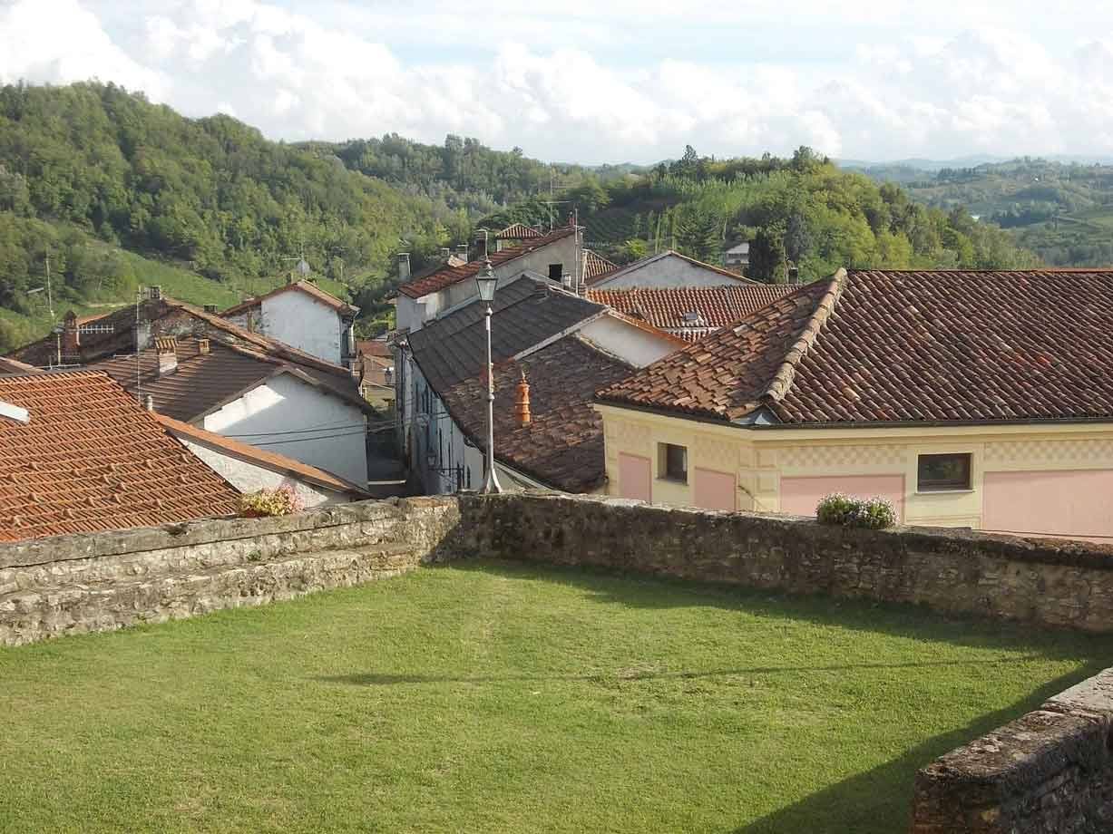 Tetti di coppi sul borgo collinare visti dal prato cinto da mura in pietra