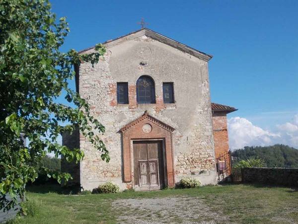 Weathered stone and brick church with wooden portal under blue sky