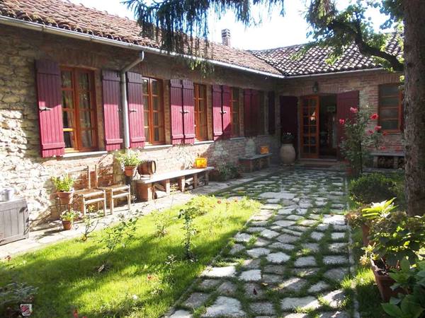 Stone farmhouse courtyard with red shutters and flagstone path