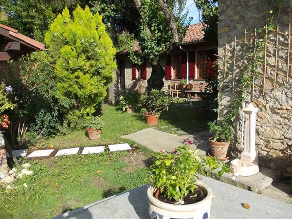 Garden with potted flowers, white stepping stones and stone farmhouse with red roofs