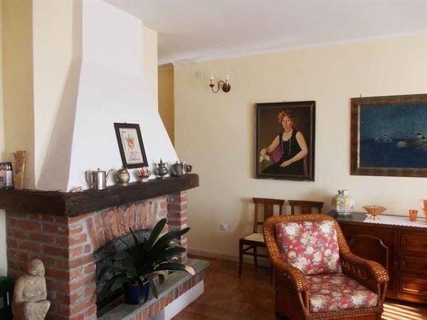 Living room with brick fireplace, painted portrait and floral wicker armchair