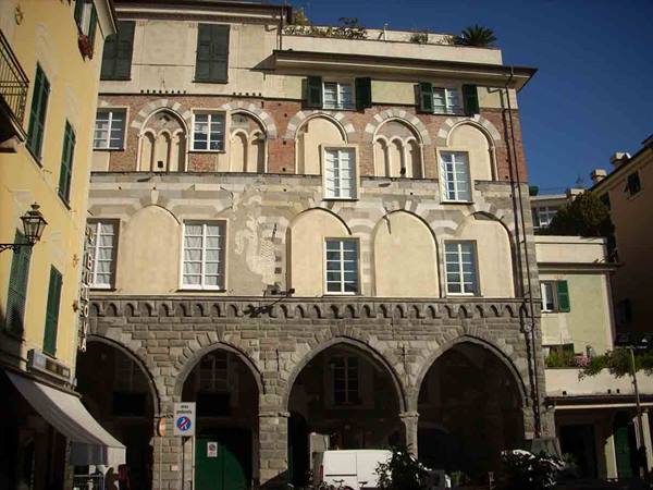 Medieval stone palace with arched loggia, two-tone facade under blue sky