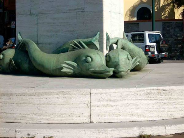Green bronze dolphin sculptures at the base of a fountain