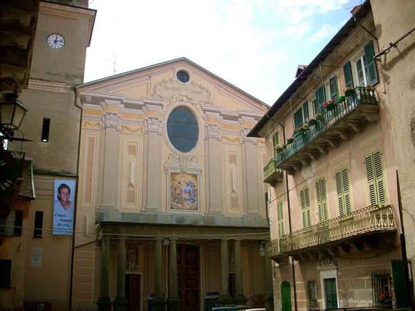 Baroque church facade with bell tower clock among buildings with flowered balconies