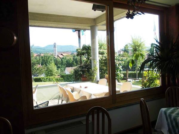 Dining room with wooden tables and chairs, window onto garden and bell tower