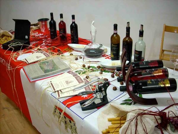 Table with red wine bottles, decanter, corkscrew and brochures on a cloth