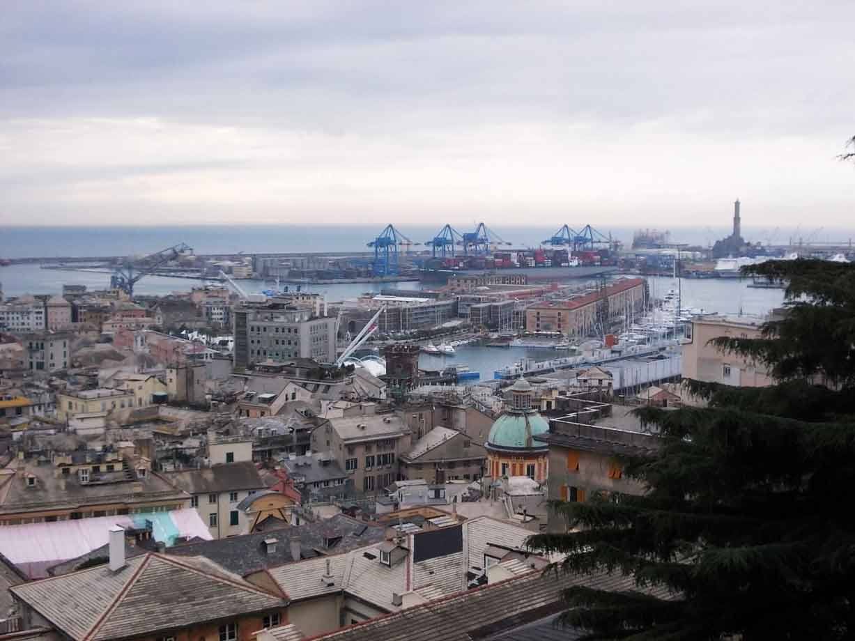 Porto antico di Genova con gru commerciali e la Lanterna sullo sfondo