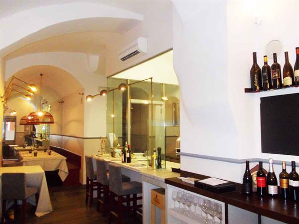 Restaurant dining room with white vaulted ceilings, marble counter and displayed wine bottles