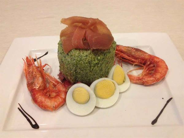 Green timbale with ham, roasted prawns and halved boiled eggs on white plate