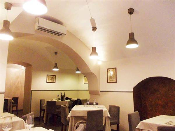 Restaurant dining room with white vaulted ceilings, set tables and glowing pendant lamps