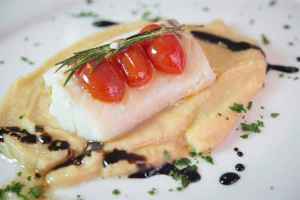 Fish fillet on fava bean cream with cherry tomatoes, rosemary and balsamic glaze