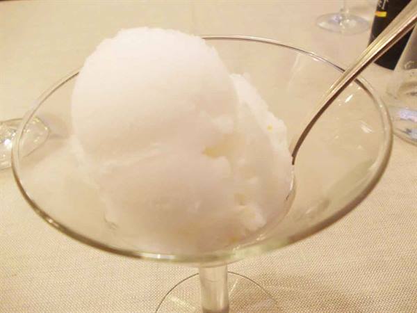 White sorbet in a glass coupe, silver spoon, warm indoor light