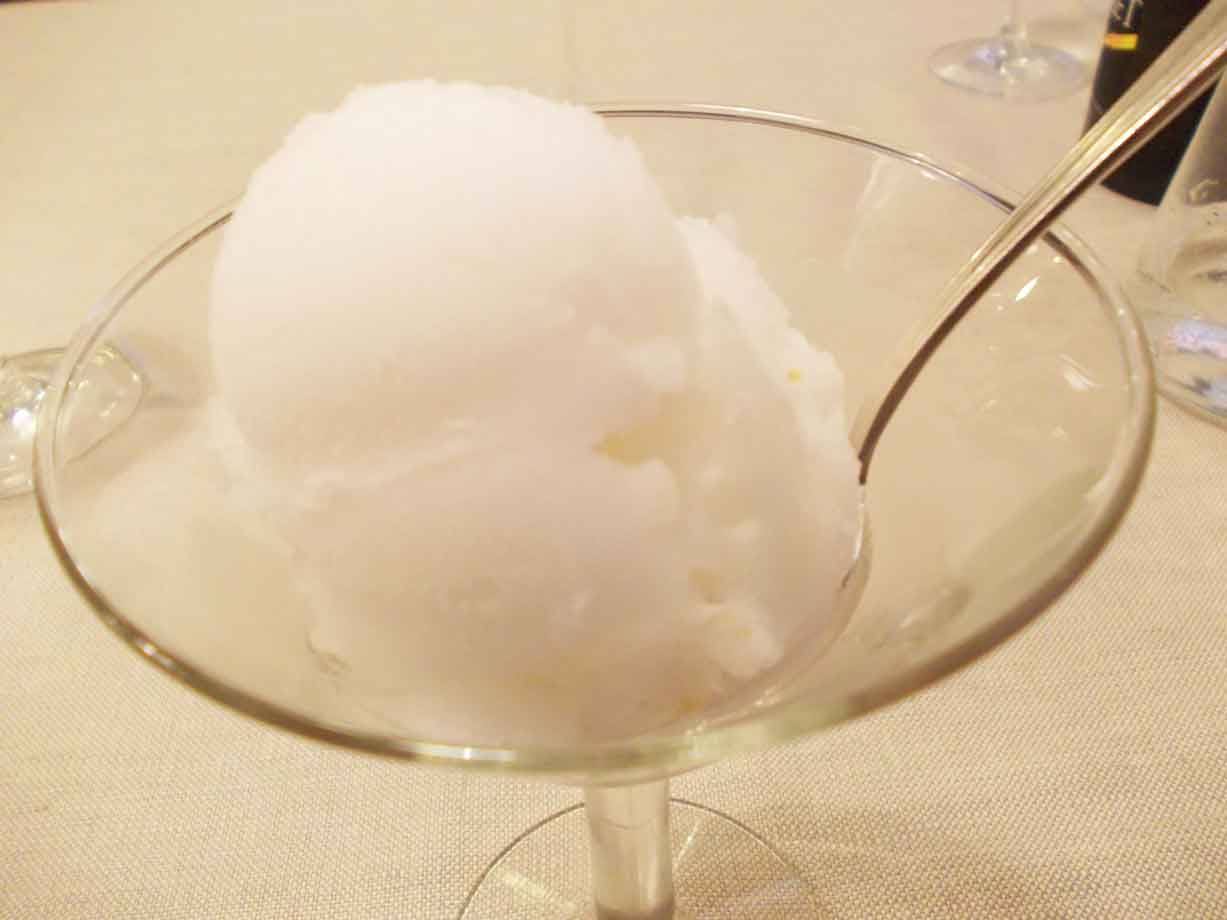 Coppetta di sorbetto bianco in bicchiere di vetro, con cucchiaio d'argento, luce calda