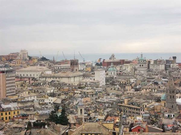 Genoa old rooftops with domes and bell towers under a grey sky