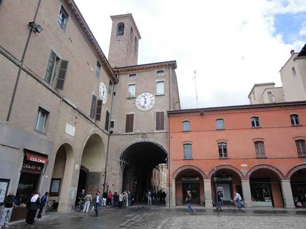 People walk under the arch of an old clock-tower building