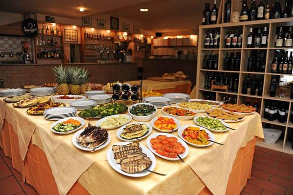 Buffet of grilled vegetables on a set table, pineapples and wine bottles in the restaurant