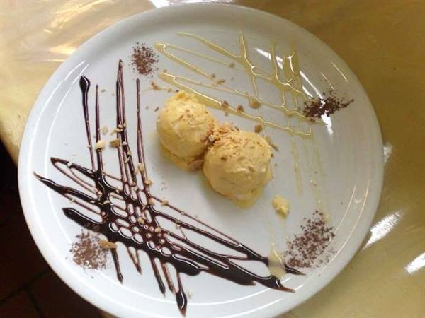 Two scoops of ice cream on white plate with chocolate and caramel