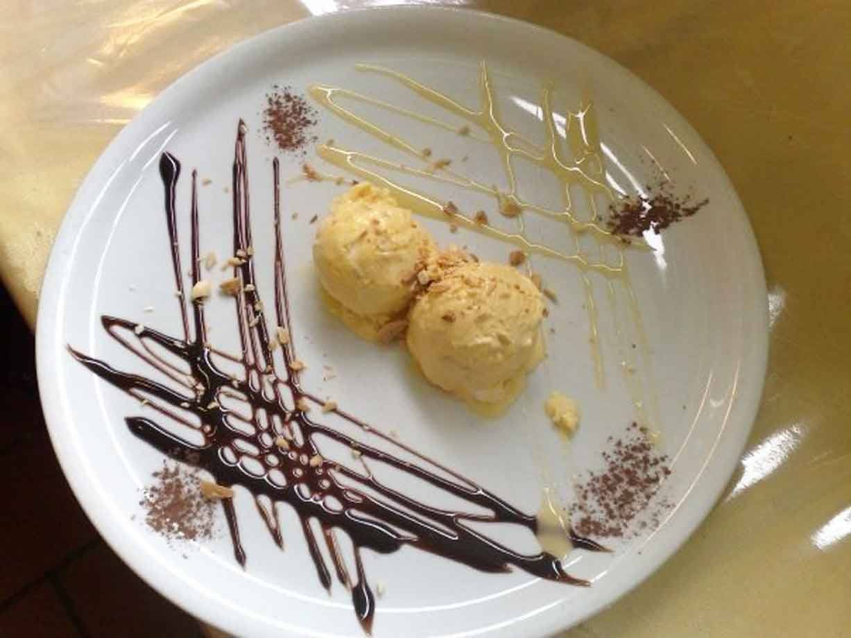 Due palline di gelato su piatto bianco con cioccolato e caramello