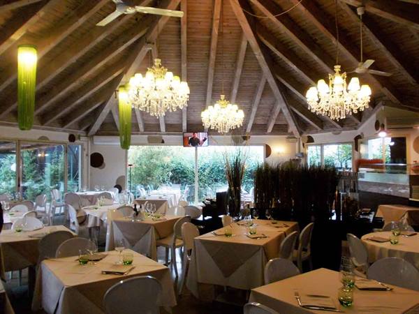 Restaurant dining room with set tables, wooden beams and illuminated crystal chandeliers