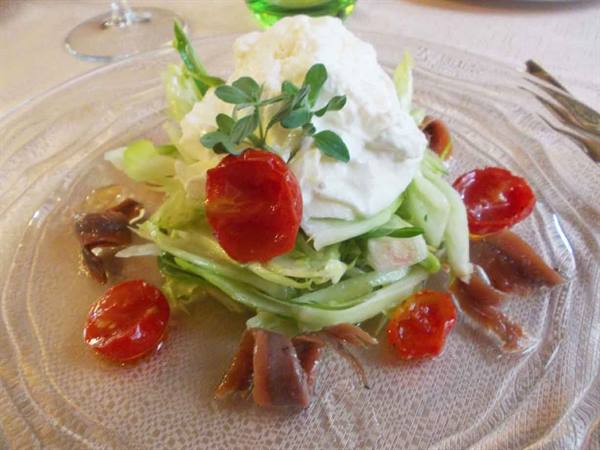 Glass plate with stracciatella, cherry tomatoes, anchovies and fresh vegetables