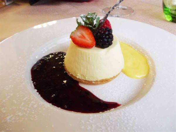 Panna cotta with strawberry, blackberry, berry coulis and mango cream on white plate