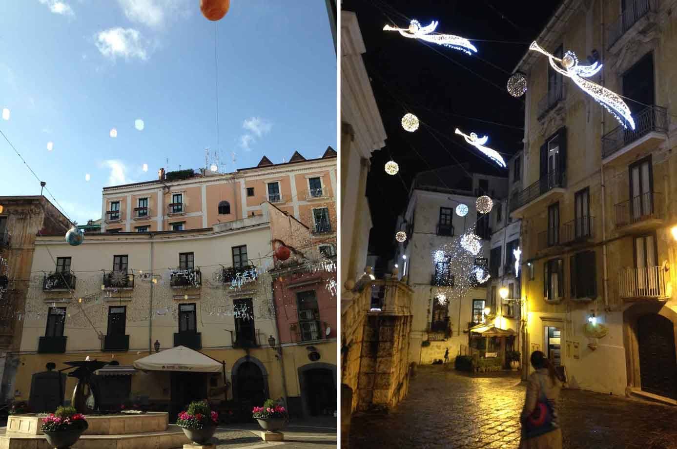 Palazzi antichi con luci natalizie sospese: angeli illuminati di giorno e di notte