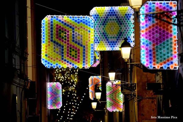 Colorful illuminated panels hanging above a night alley among lit street lamps