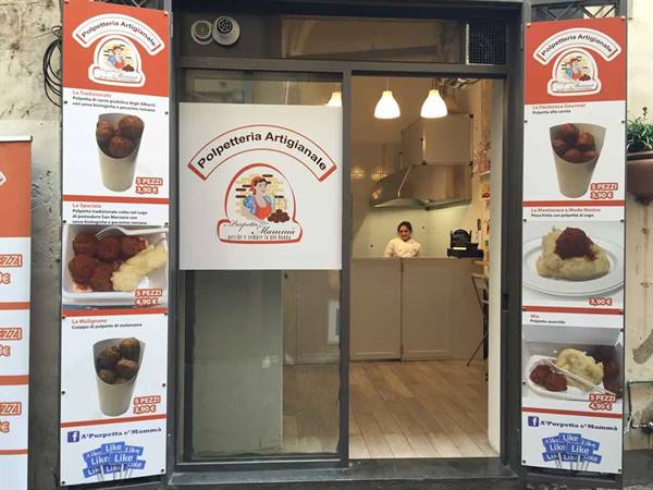 Entrance of Polpetteria Artigianale, orange menu signs, a cook behind the counter