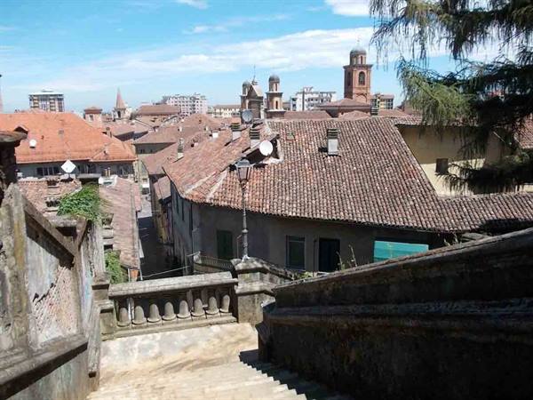 Stone staircase between brick rooftops and bell towers under blue sky