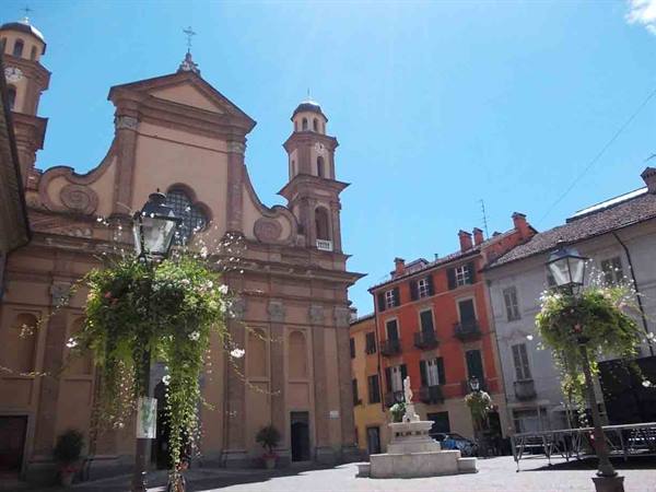 Baroque brick church with bell towers and fountain in a sunny square
