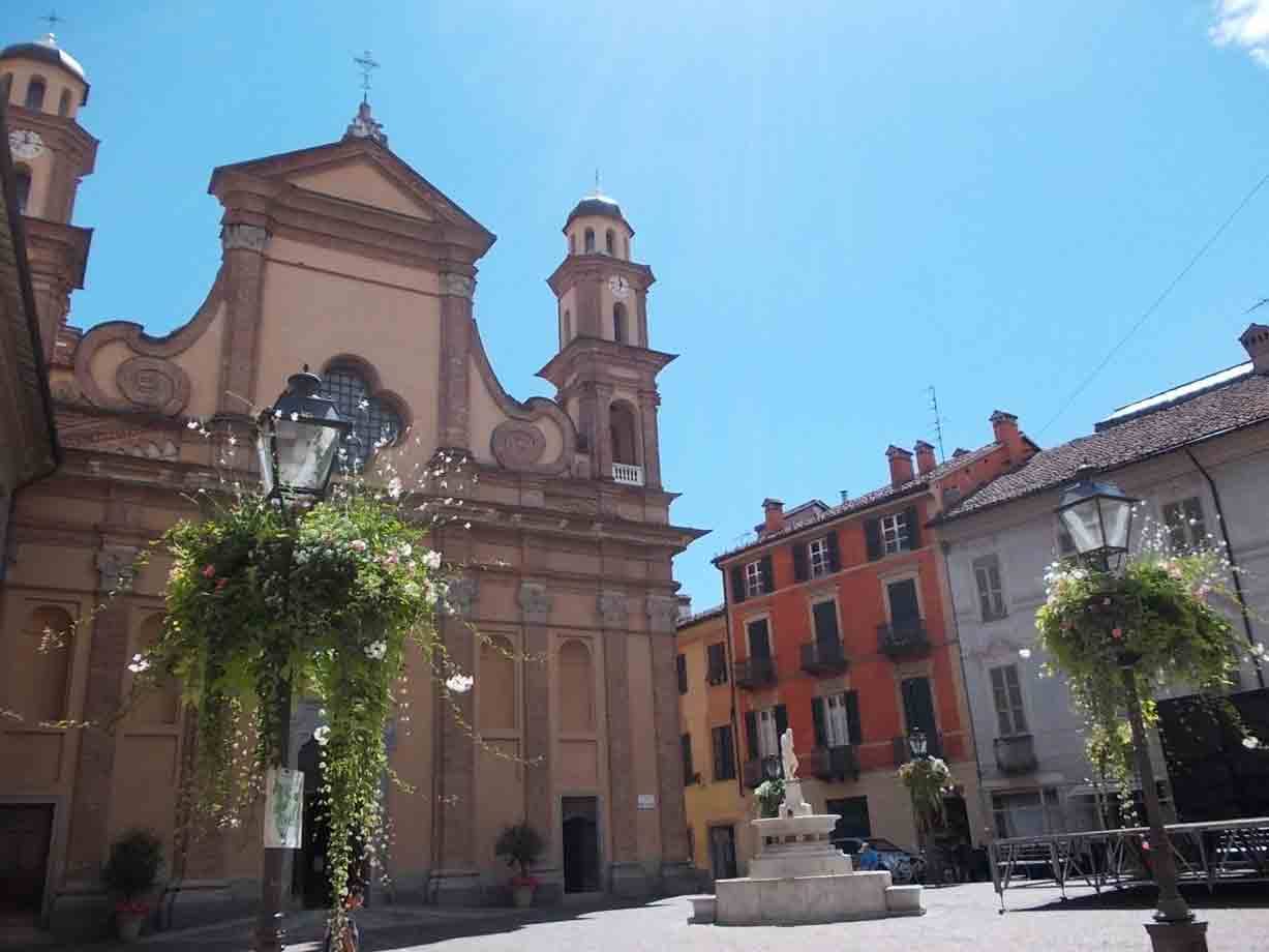Piazza con chiesa barocca in mattoni, campanili e fontana al centro