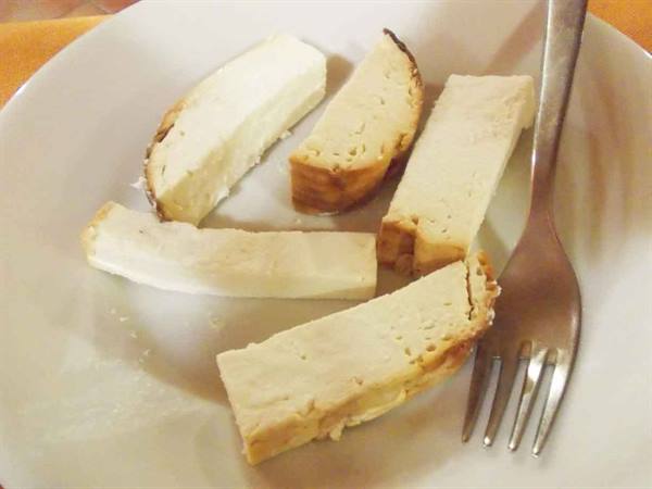 Slices of white cheese on a flat plate, steel fork beside