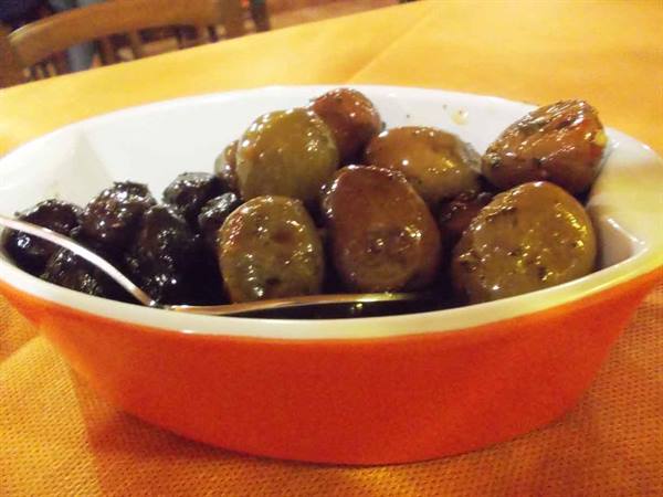 Orange bowl with green and black olives in oil on table