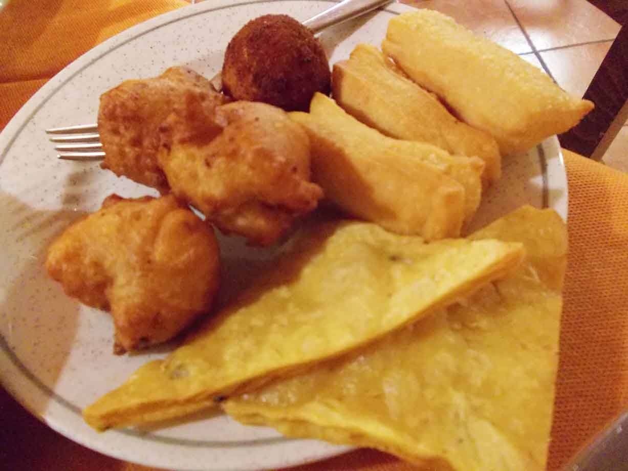 Piatto di fritti siciliani: panelle, arancina e focaccia su tavolo