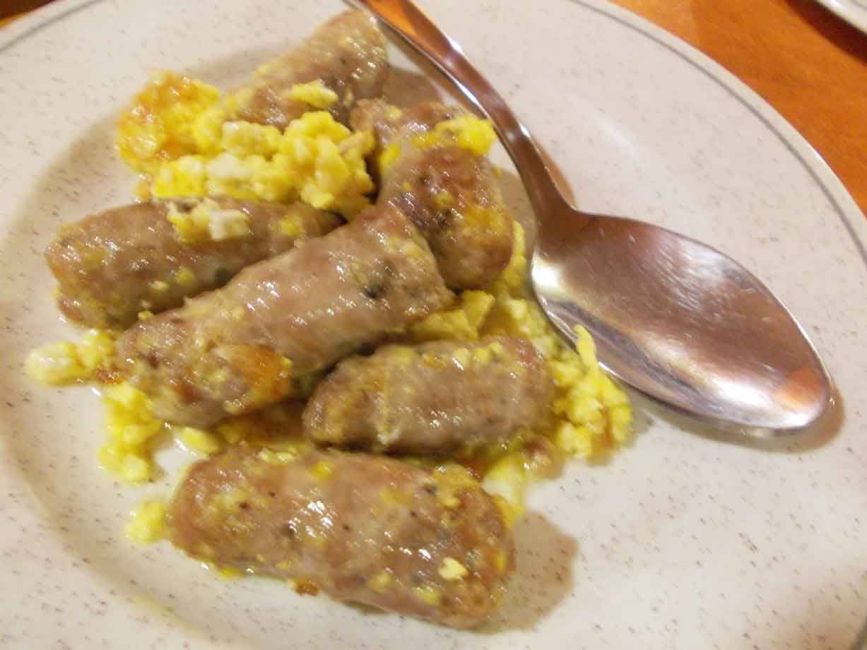 Salsicce saltate con uovo strapazzato su piatto di ceramica, luce interna