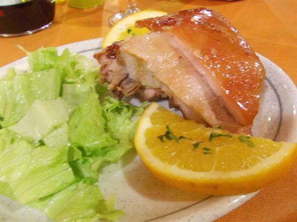 Glossy roast pork served with lettuce and fresh orange wedges