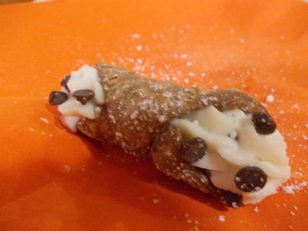 Sicilian cannoli with ricotta and chocolate chips on orange paper