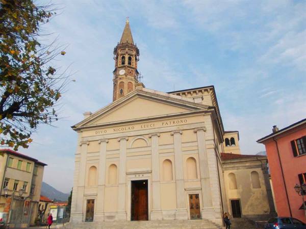 Basilica of San Nicolò in Lecco, pale facade and bell tower under blue sky