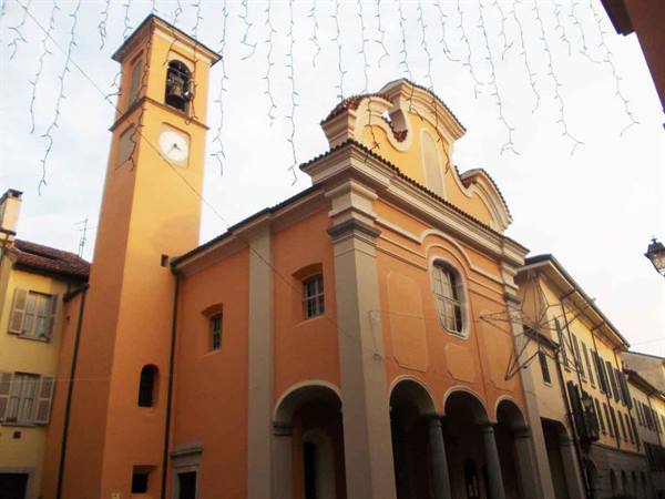 Orange baroque church with bell tower and clock, Christmas lights overhead