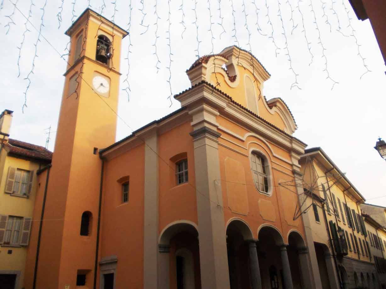 Chiesa barocca arancione con campanile e orologio, luci natalizie appese