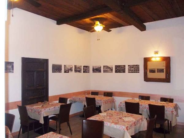 Restaurant dining room with set tables, wooden beams and vintage photographs on walls
