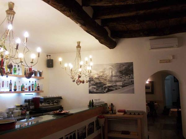 Interior bar with lit golden chandeliers, wooden beams and bottles on shelves