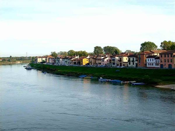 Covered boats moored along the river in front of colorful houses at San Nazzaro Sesia